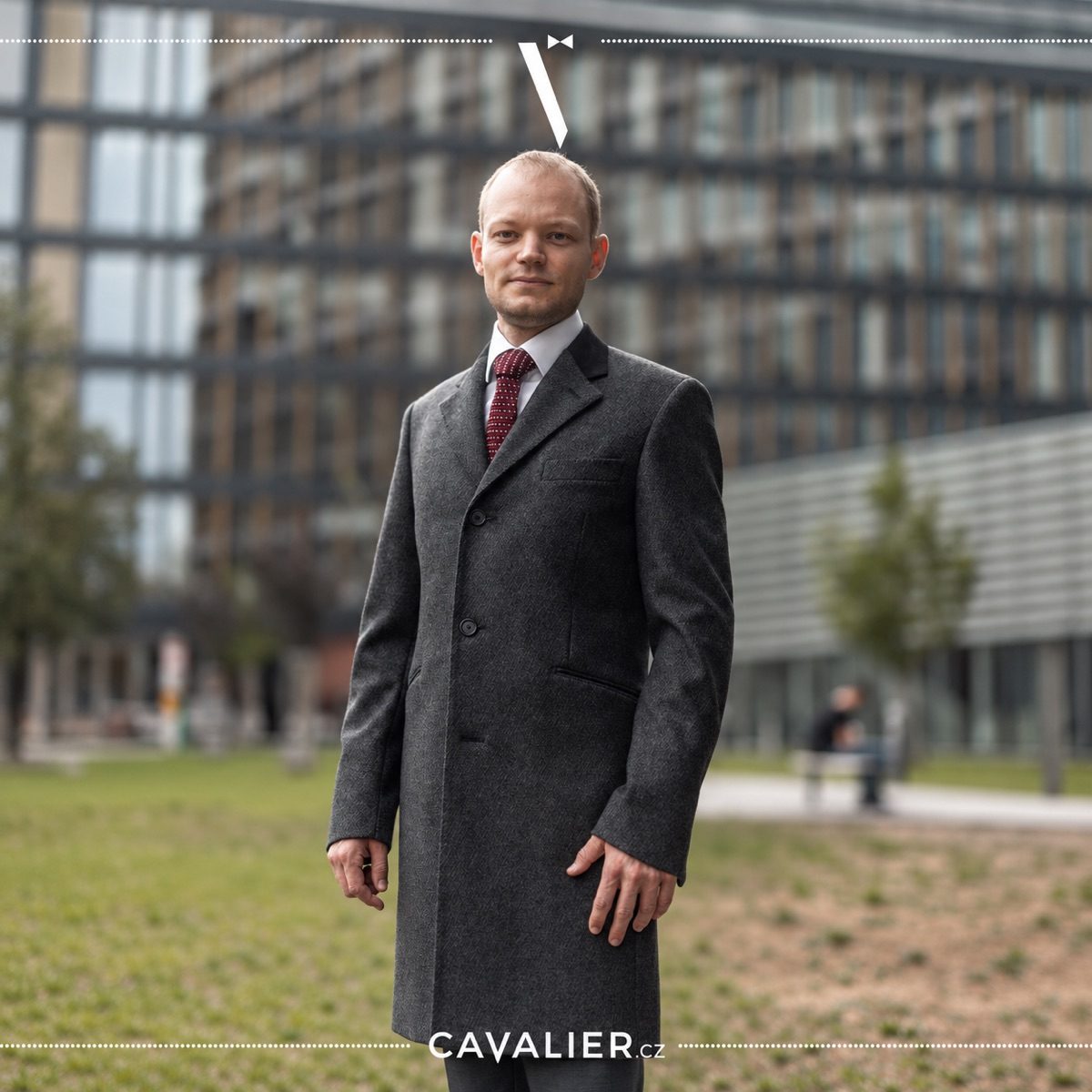 Šedý pánský kabát na míru v elegantním business outfitu s košilí a kravatou.