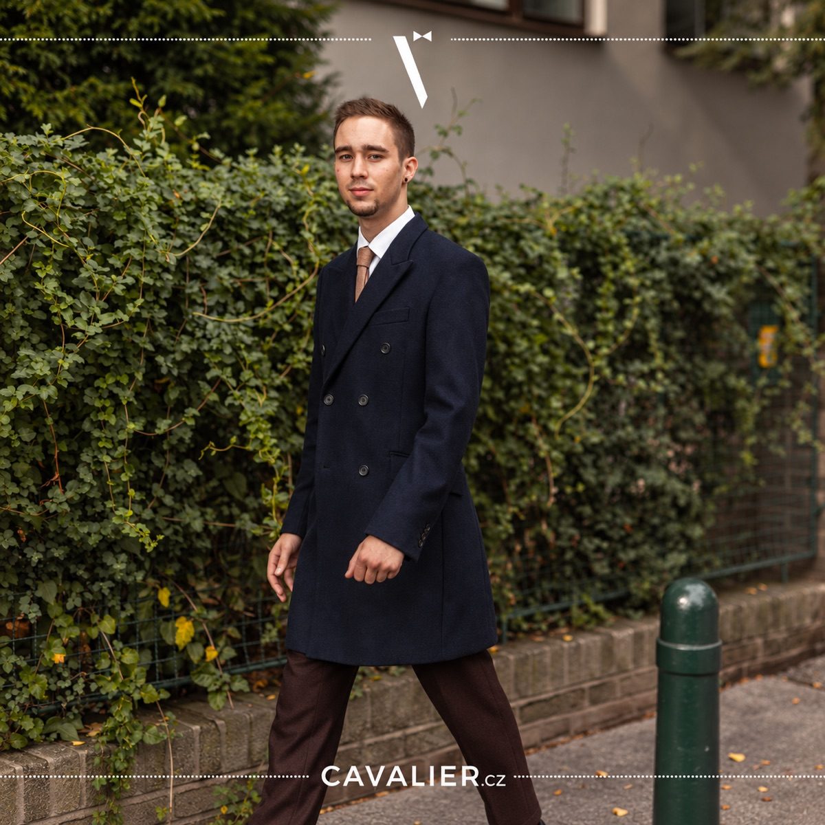 Tmavě modrý dvouřadý kabát na míru v moderním pánském městském outfitu.