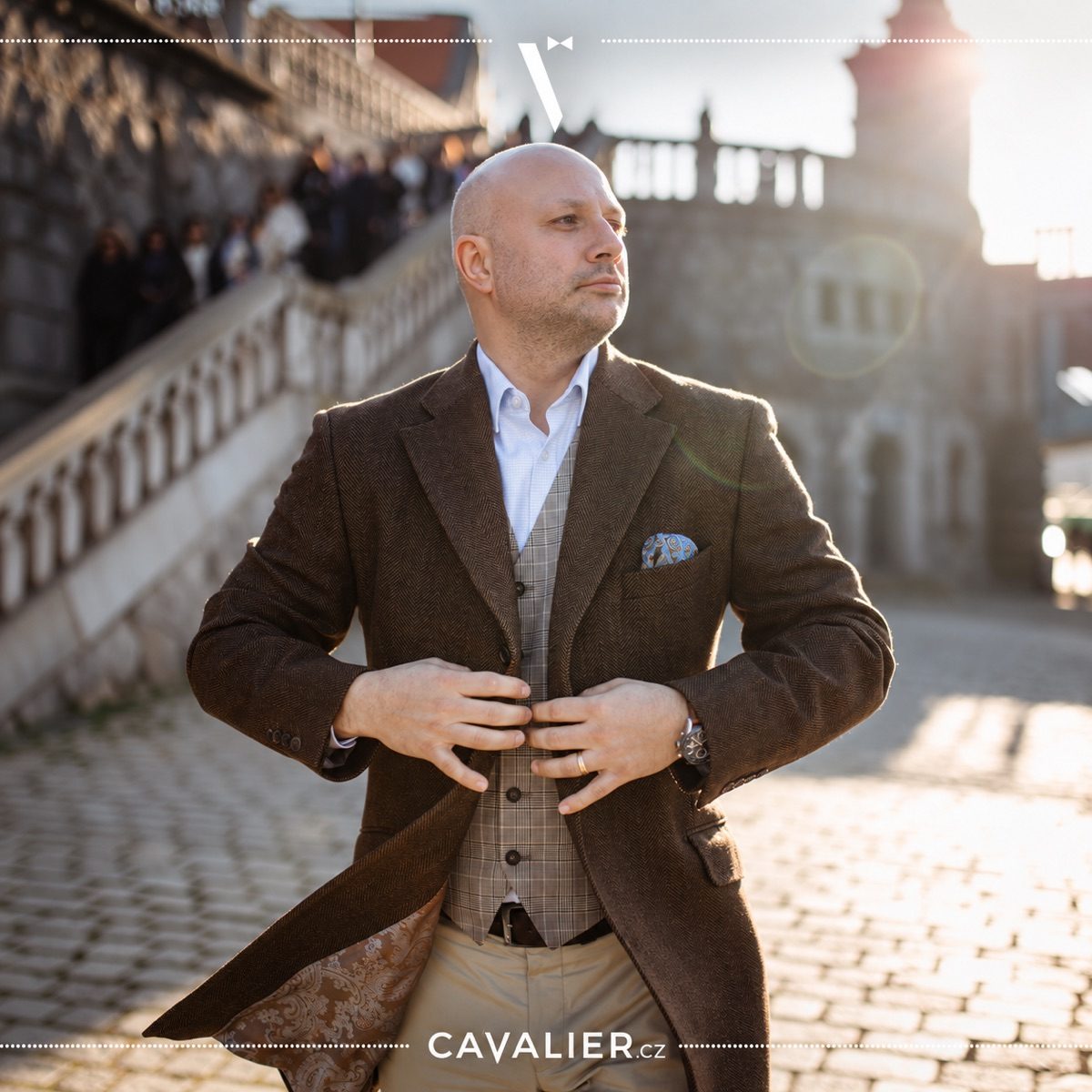 Muž v hnědém tvídovém saku na míru a vestě v elegantním smart casual outfitu.