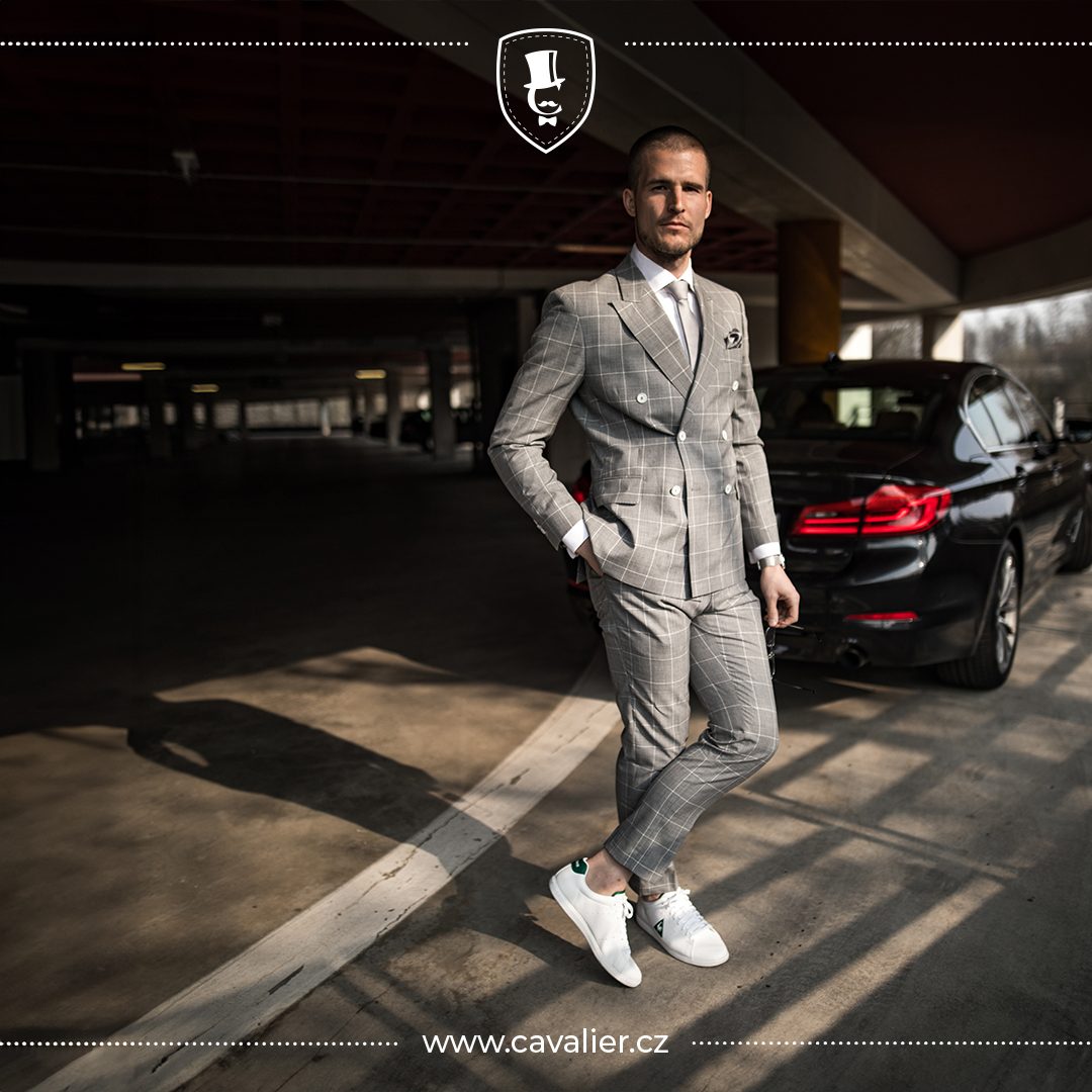 Muž v šedém kostkovaném dvouřadém obleku na míru Cavalier představující elegantní styl při výběru pánského obleku