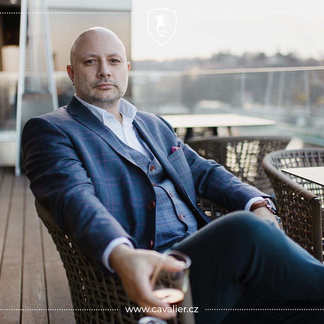 Eleganční muž v modrém kostkovaném obleku na míru Cavalier s vestou na terase