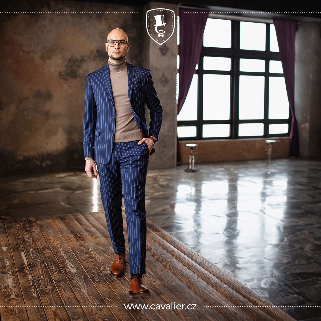 Muž v modrém proužkovaném obleku na míru Cavalier doplněném hnědým rolákem jako trik pro stylové a elegantní vrstvení