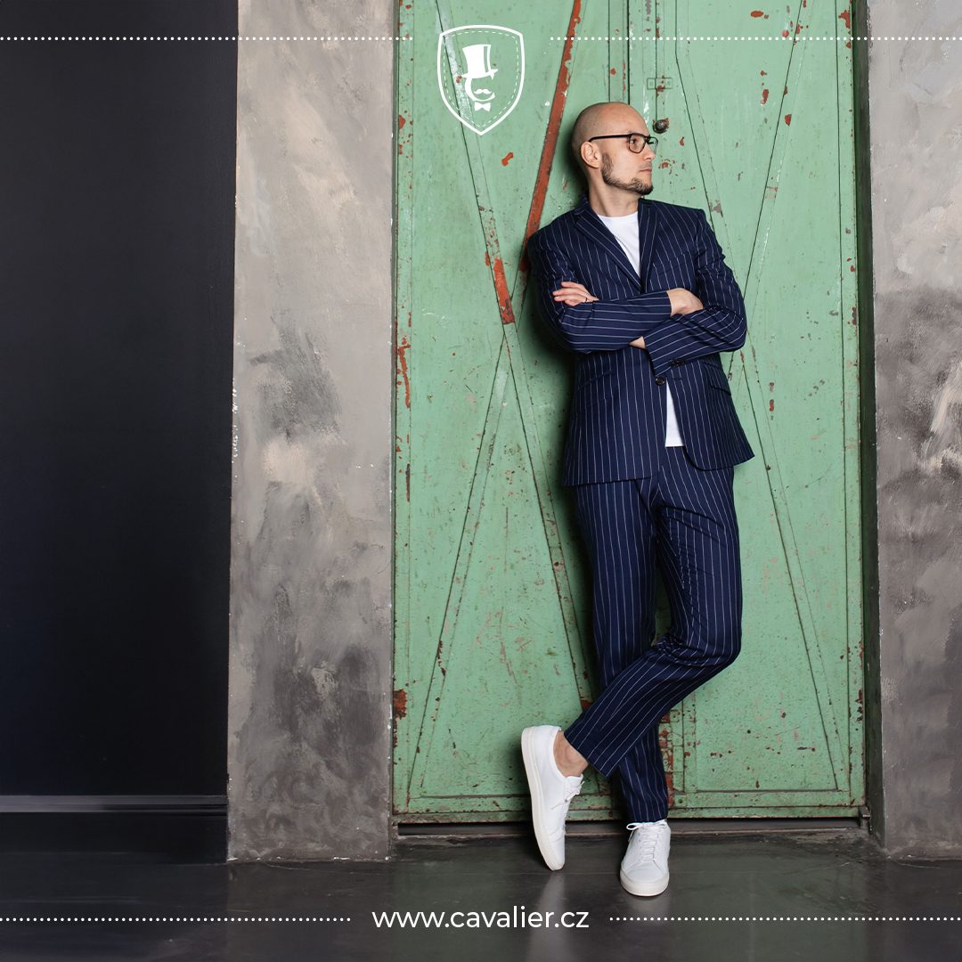 Muž v modrém proužkovaném obleku na míru Cavalier zkombinovaném s bílým tričkem a tenisky jako trik pro ležérní smart casual styl
