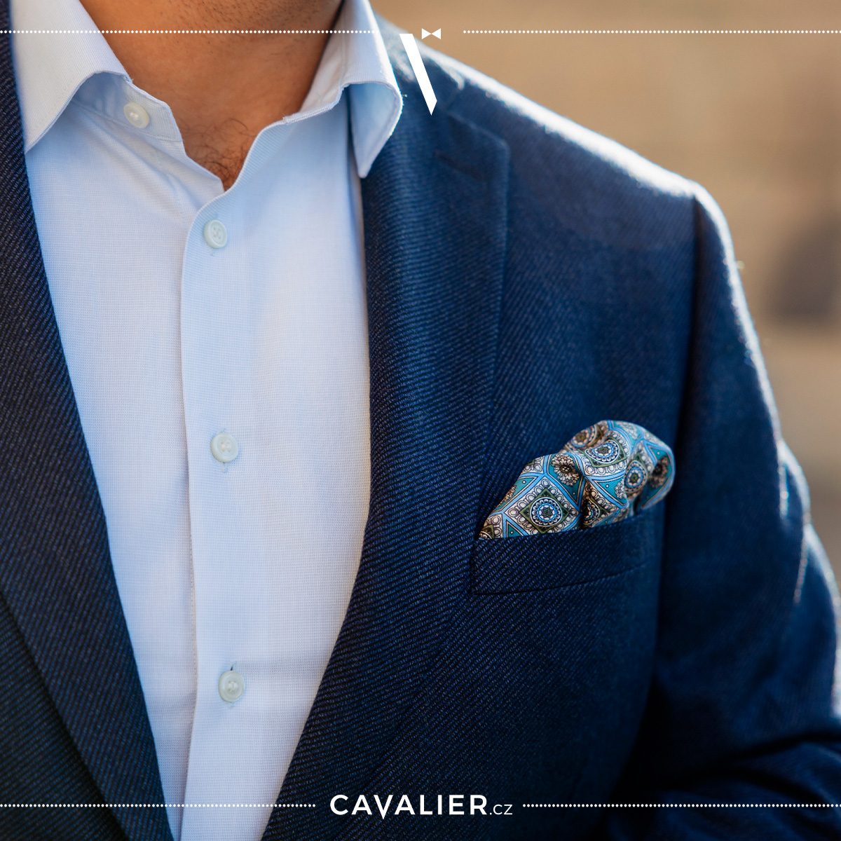 Detail elegantního barevného sladění – tmavě modré strukturované sako Cavalier doplněné světle modrou košilí a výrazným vzorovaným kapesníčkem v modro-zelených tónu.